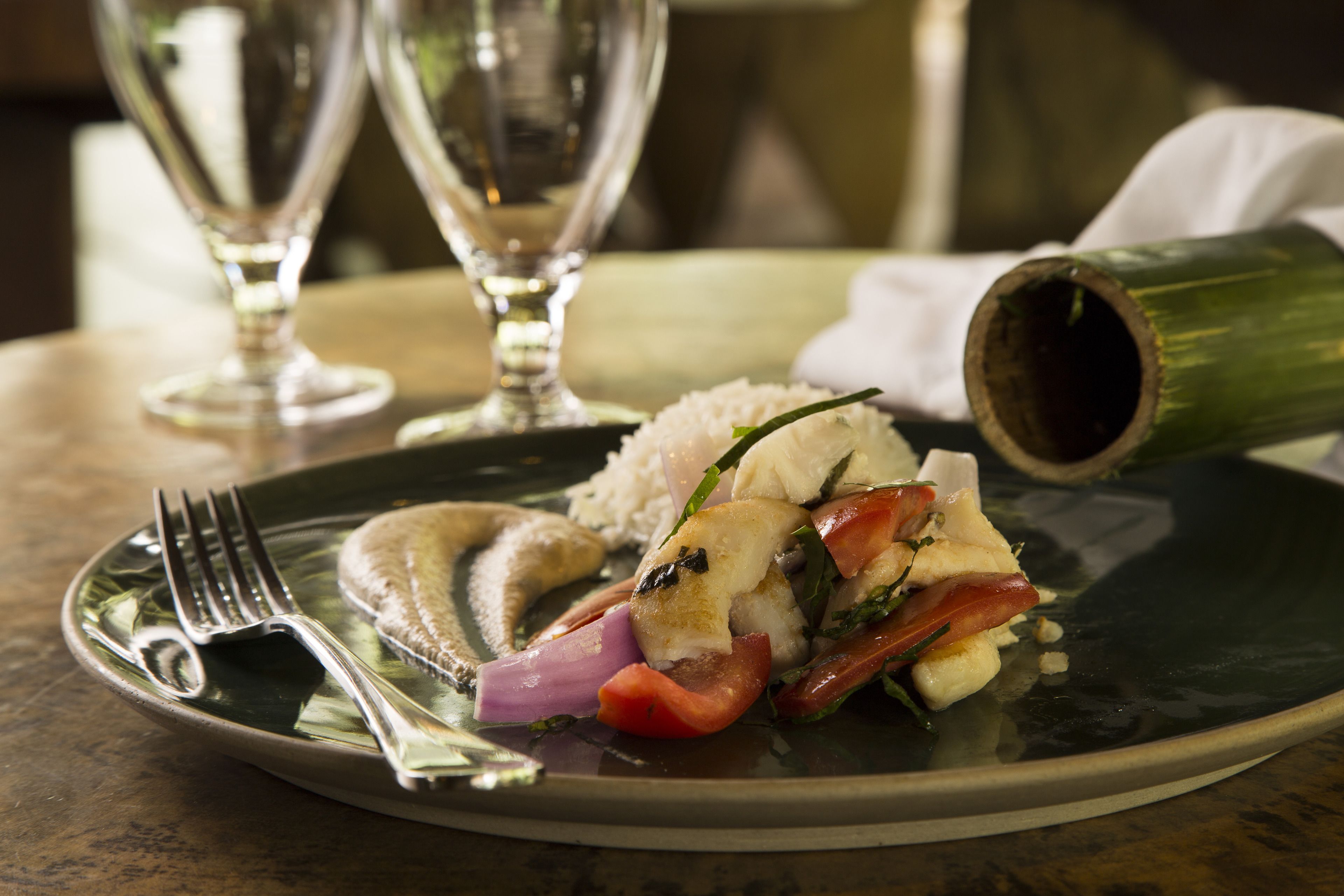 A plate of food with a fork and a glass of water on a table.