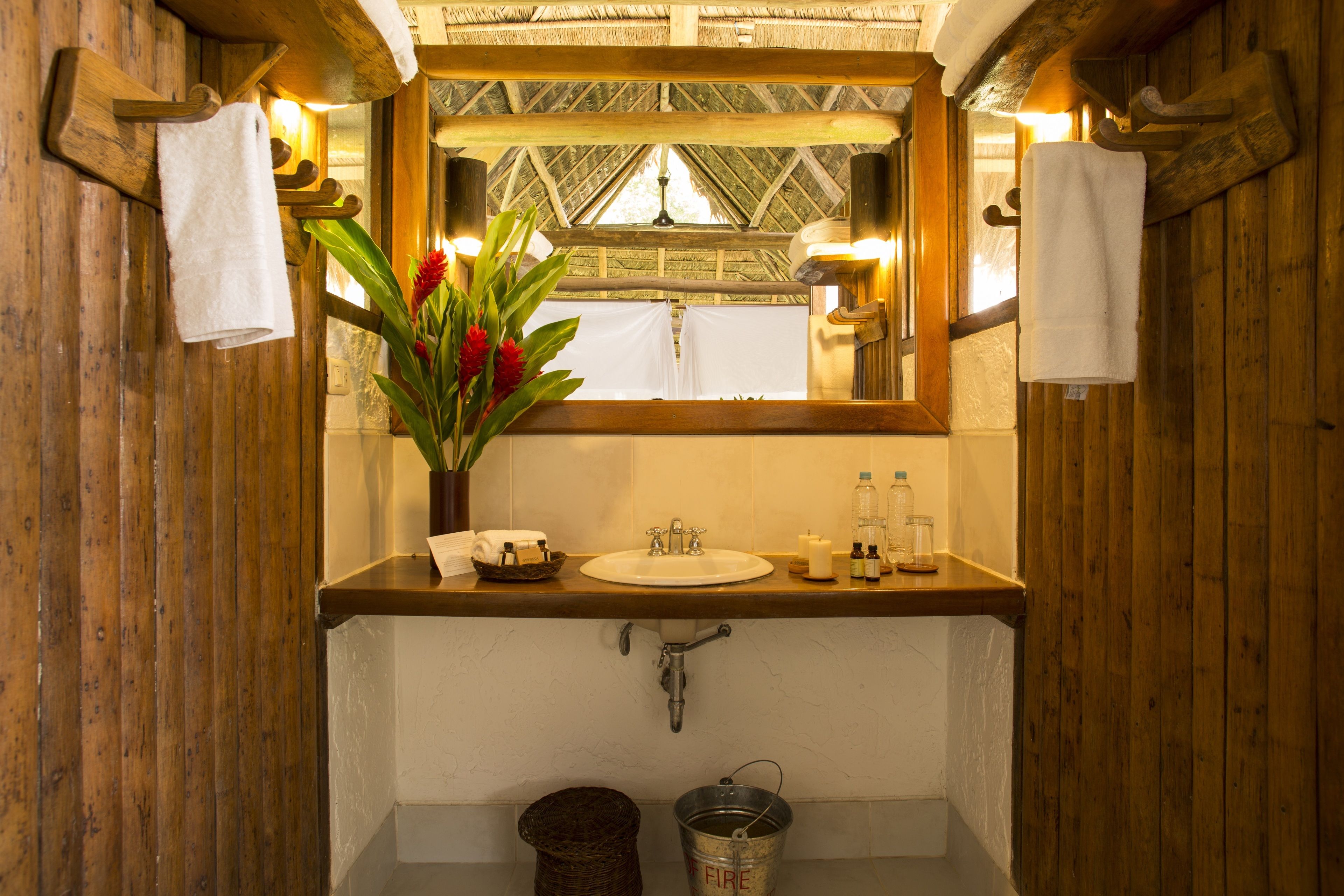 Un baño de madera con lavamanos de madera, un espejo y un florero con flores.