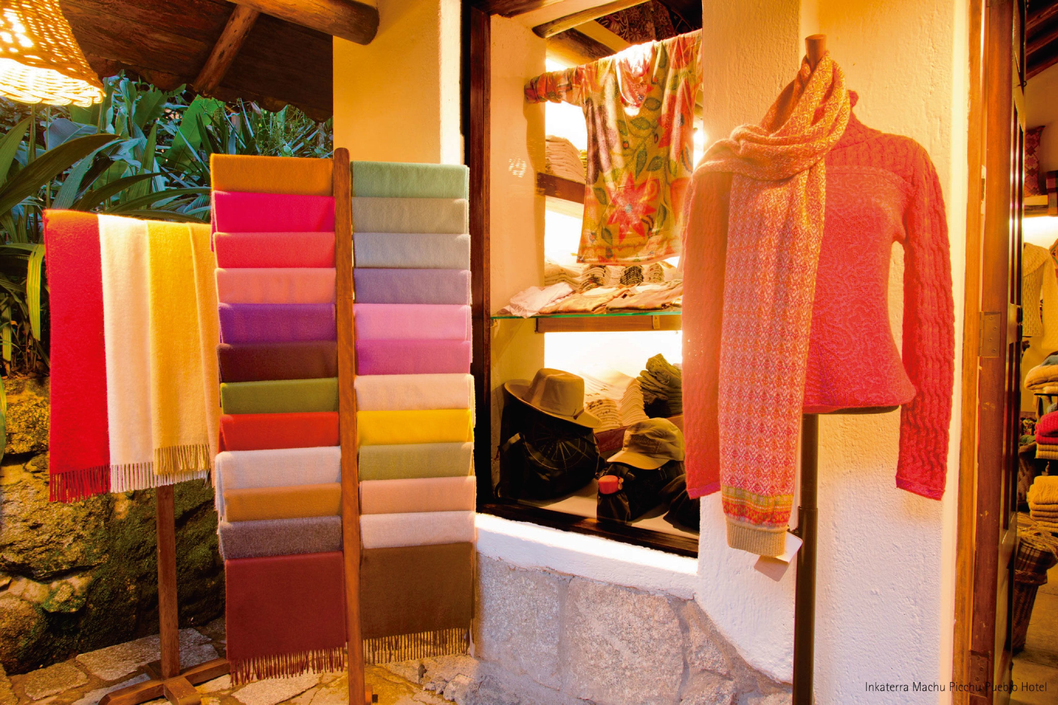 Exposição de tecidos e chapéus coloridos numa vitrine.