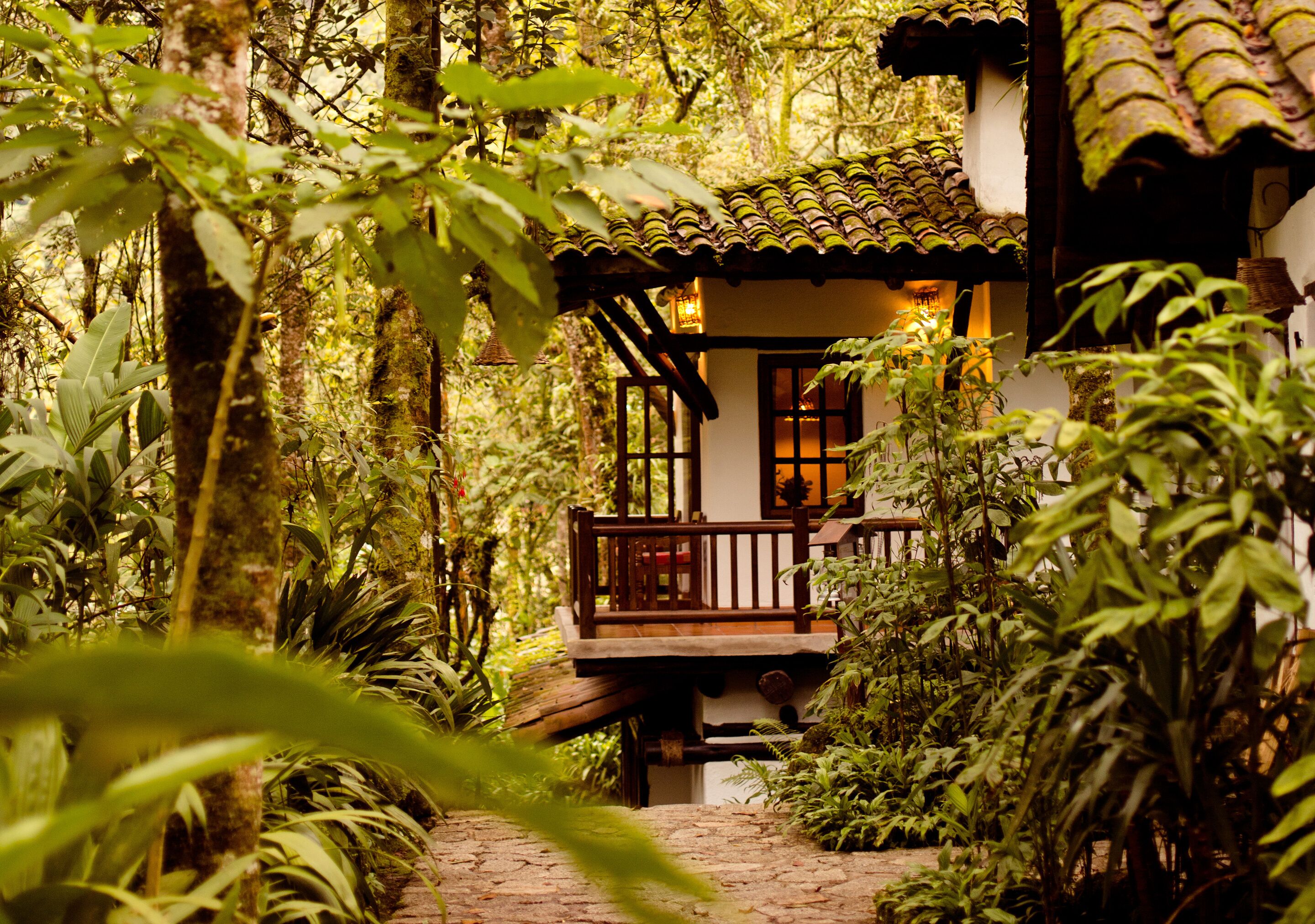 Una casa de madera con balcón, rodeada de exuberante vegetación tropical.