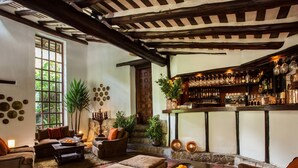Un rincón de bar acogedor con vigas de madera, barra y una selección de botellas y vasos.