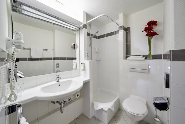 A modern bathroom with a white sink, mirror, toilet, and shower.