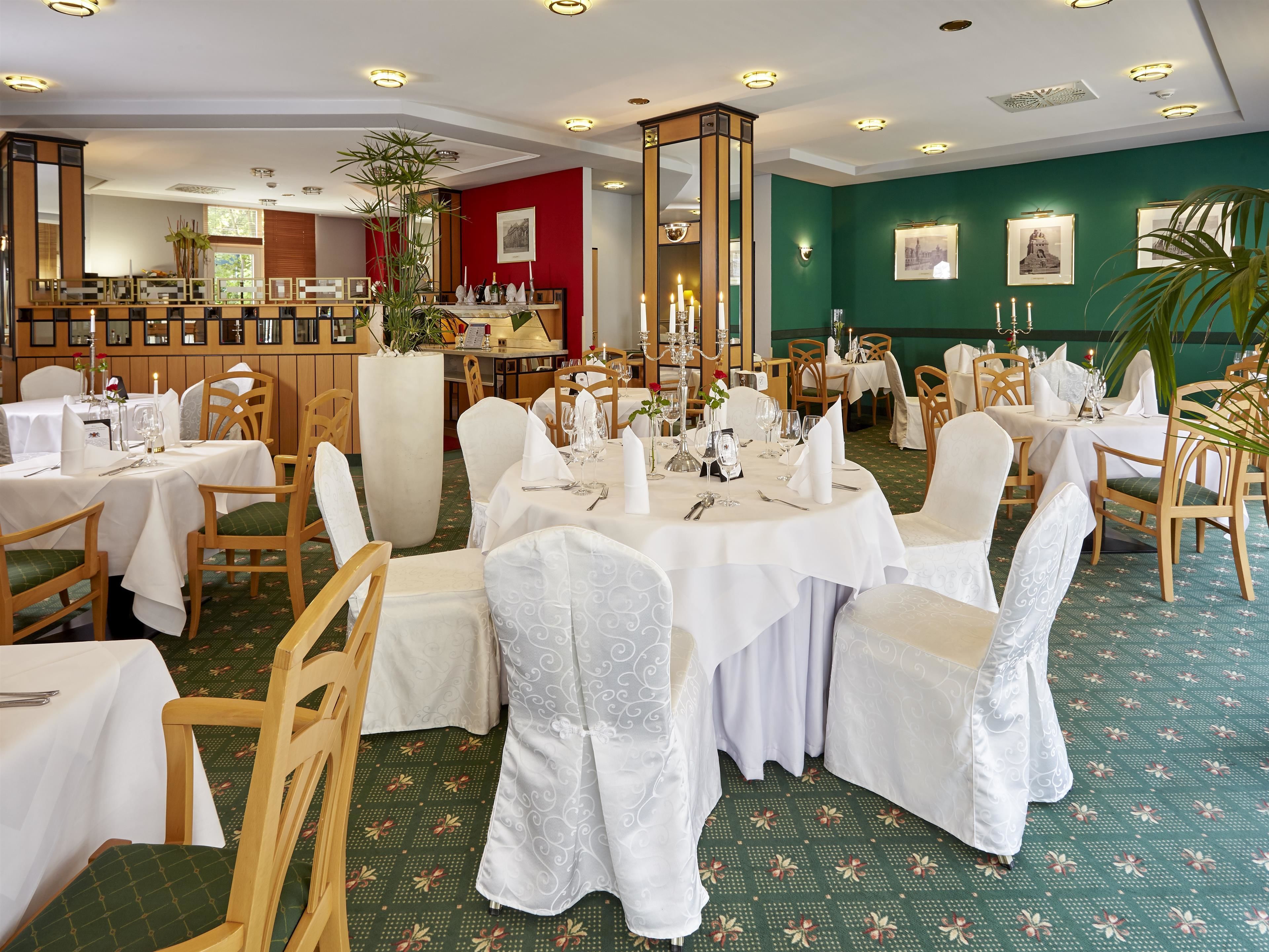 Un restaurante con mesas redondas, manteles blancos y sillas de madera.