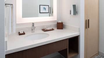 Une salle de bain moderne avec un grand miroir, un lavabo blanc, des meubles en bois et un porte-serviettes.