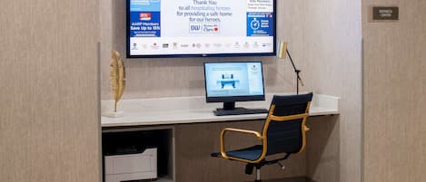A hotel workspace with a computer, chair, and desk.