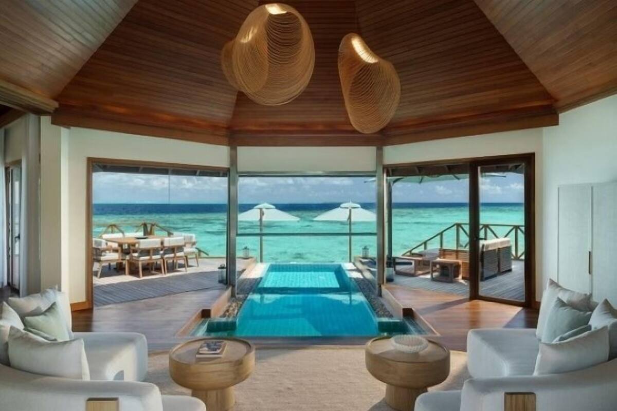 Ein luxuriöser Infinity-Pool mit freiem Blick auf das Meer, einer Holzbalkendecke und moderner Möbel.