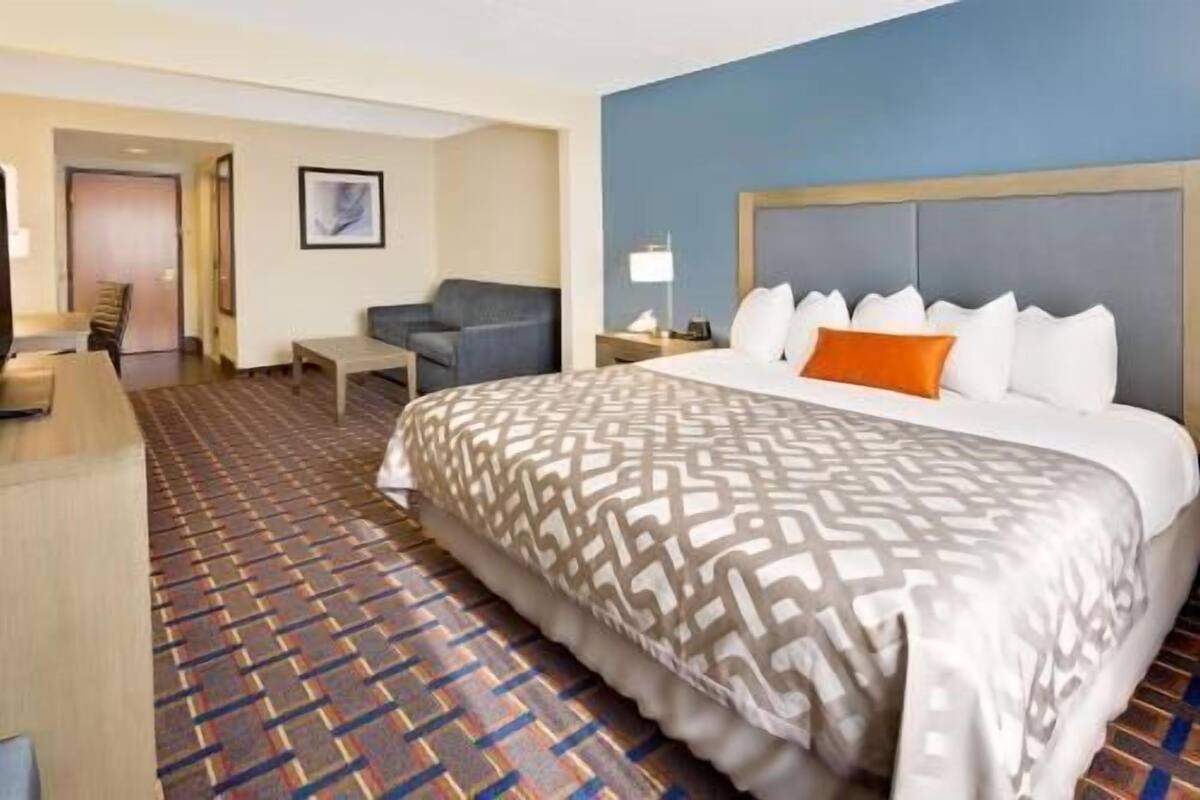 A hotel room with a large bed, a desk, a chair, and a small table.