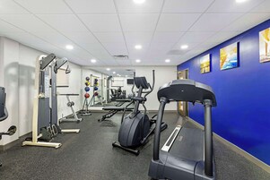 Un gimnasio con cintas de correr, máquinas de pesas y pelotas de ejercicio.