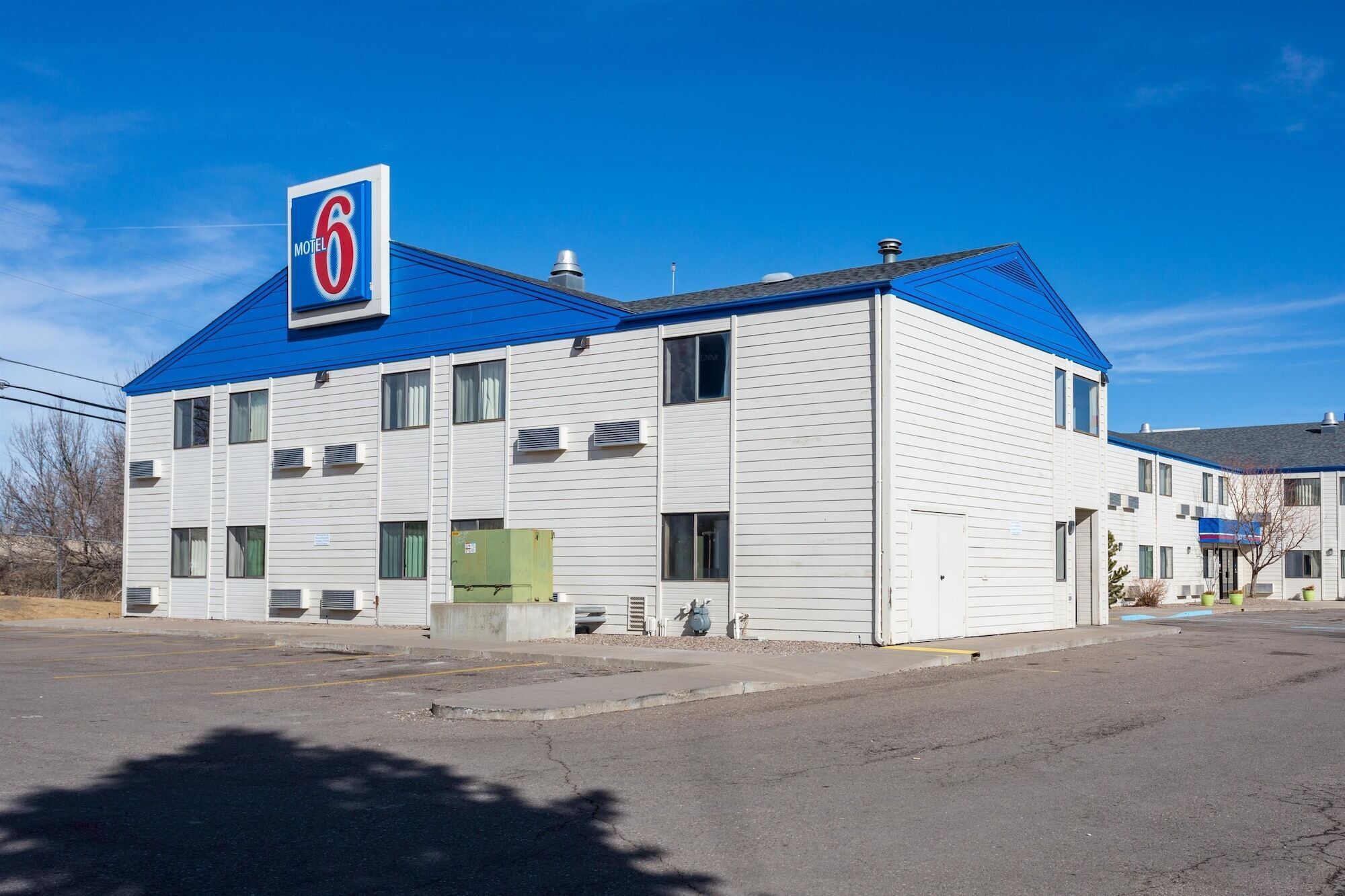 Edifício do Motel 6 com telhado azul, revestimento branco e várias janelas.