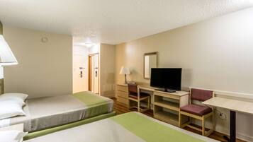 A hotel room with two single beds, a desk with a chair, a television, and a mirror.