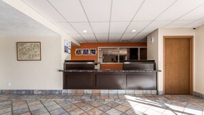 A reception area with a counter, a wooden door, and a tiled floor. - Motel 6 Great Falls, MT (Great Falls)