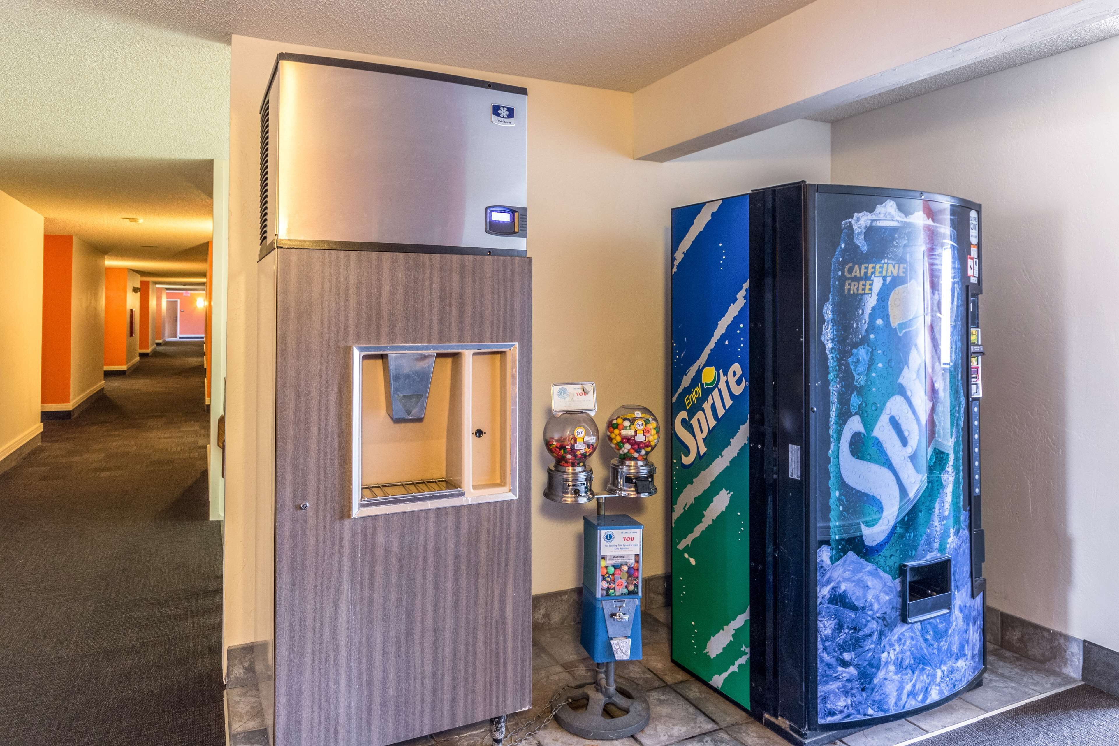 A hallway with a refrigerator, a Sprite vending machine, and a coffee machine.