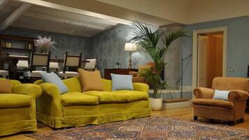 A living room with a yellow sofa set, a brown armchair, and a patterned rug.