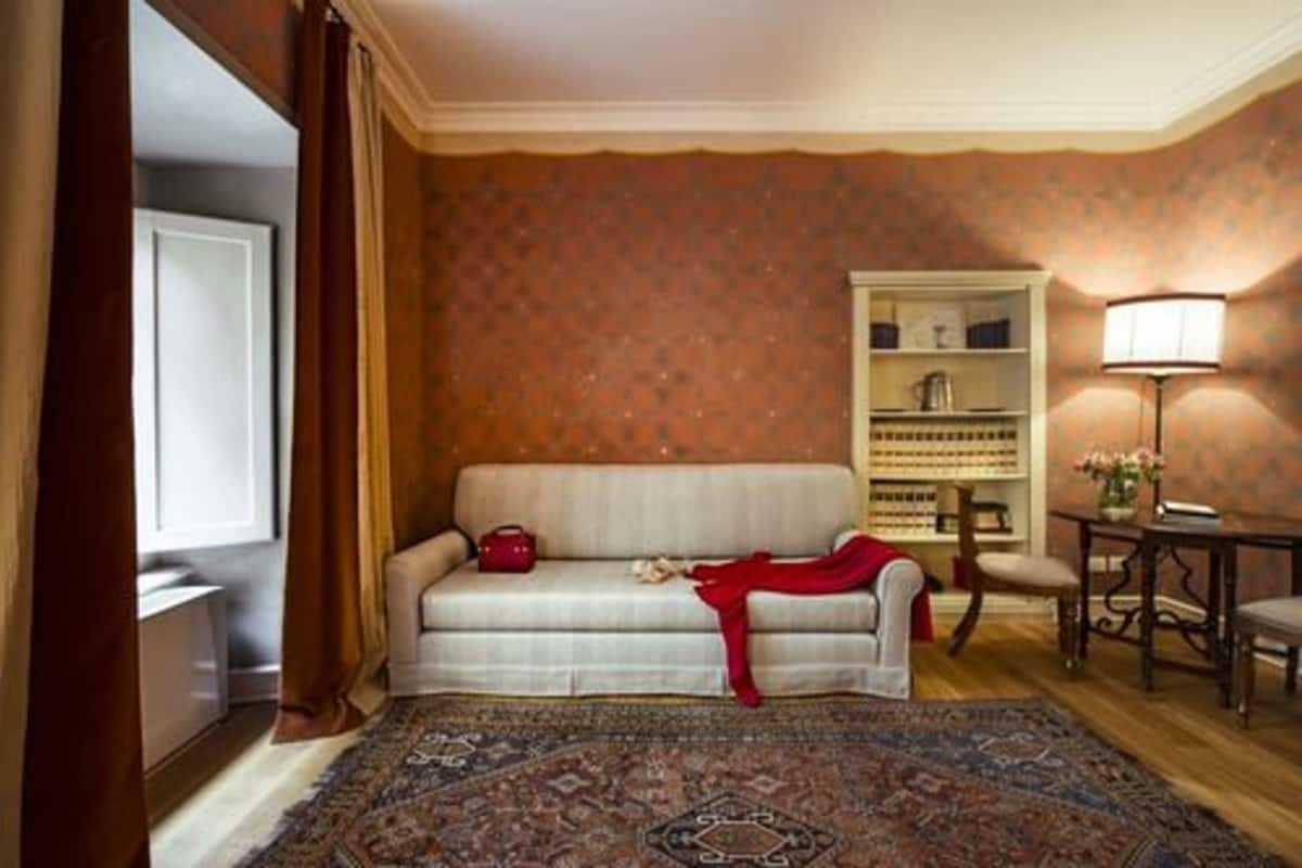 Un salon chaleureux avec un canapé, un tapis à motifs, une bibliothèque et une lampe.