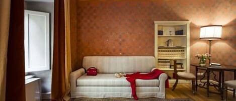 A cozy living room with a sofa, a patterned rug, a bookshelf, and a lamp.