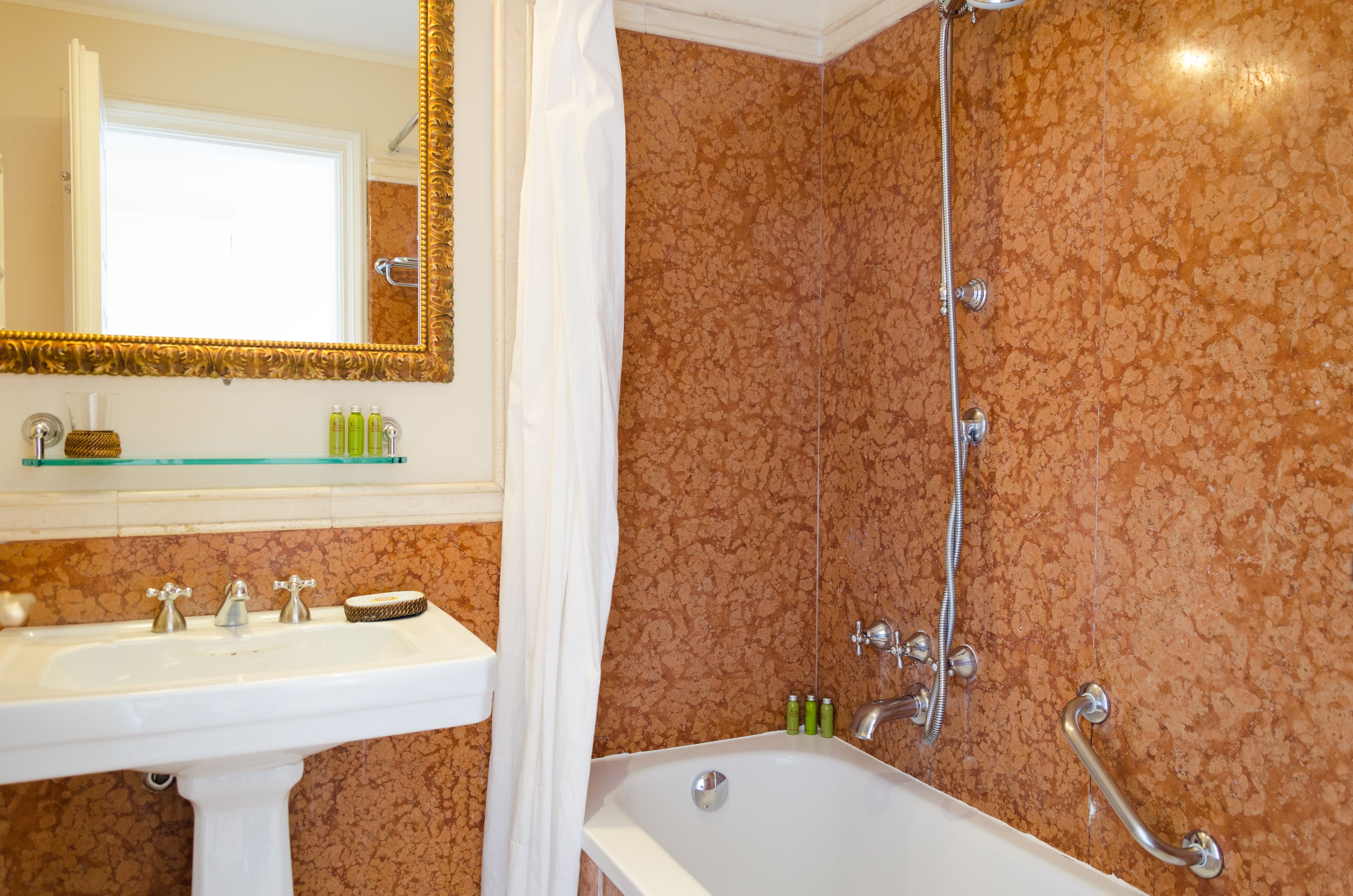 Un baño con lavabo, espejo, ducha y perchero.