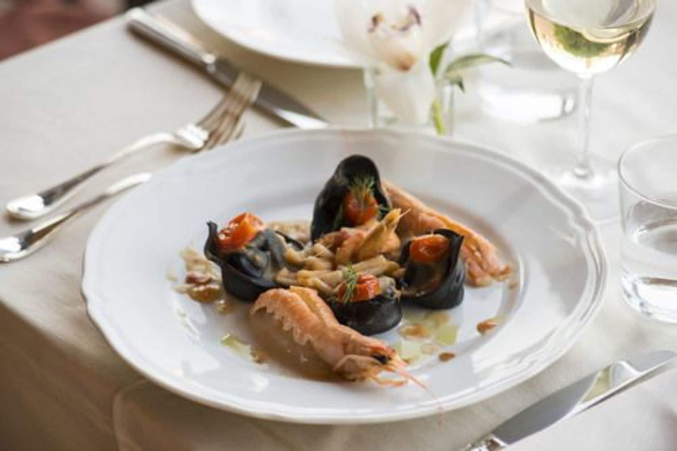 A seafood dish on a white plate with a fork and knife beside it.