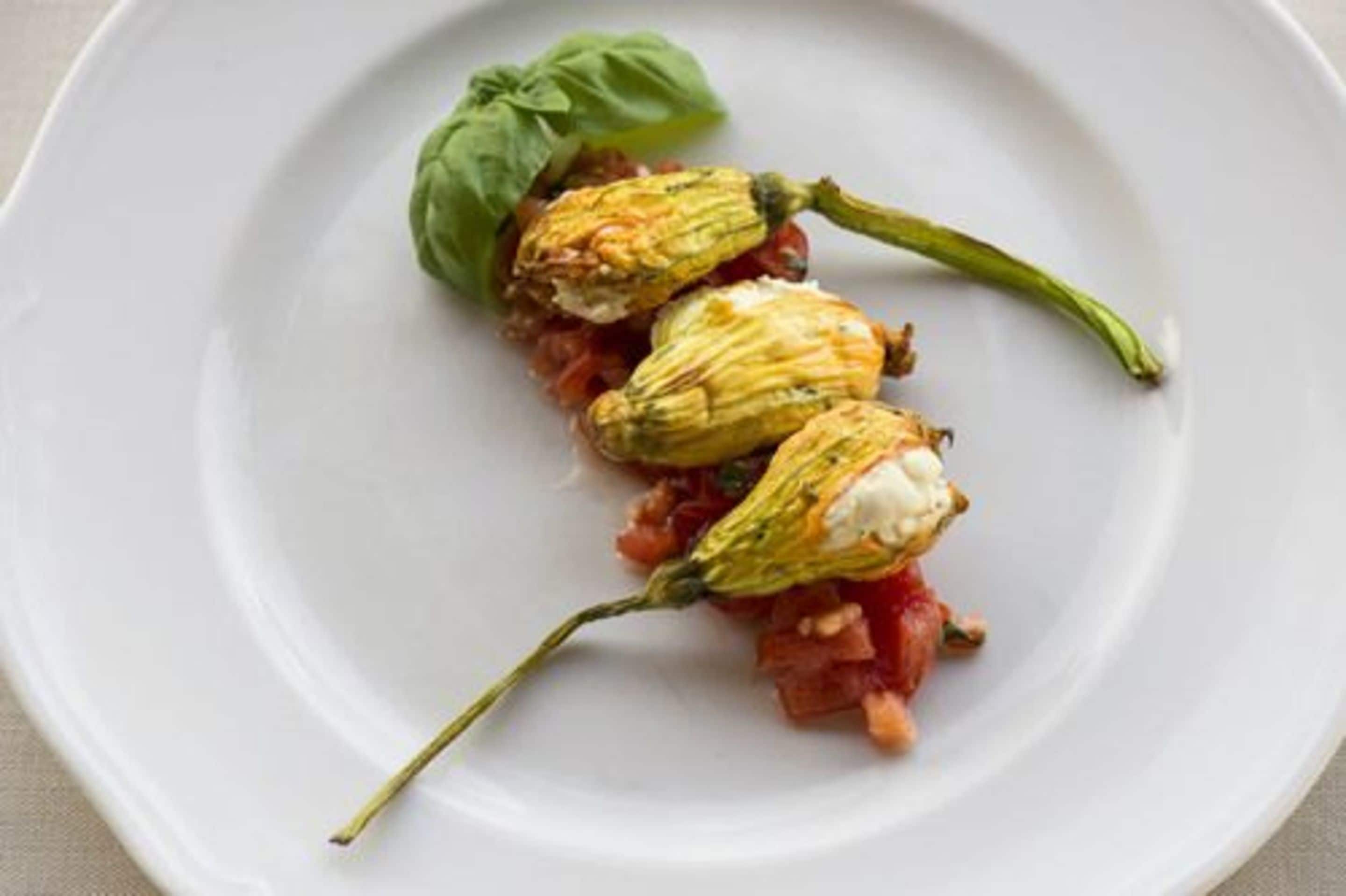 Stuffed peppers with a basil leaf on a white plate.
