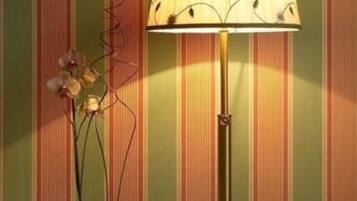 A round table with a lamp and a potted plant against a striped wall.