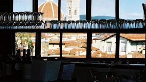 Un bar avec des bouteilles et des verres exposés sur des étagères, un menu et une vue sur un dôme et des bâtiments, visibles à travers de grandes fenêtres.