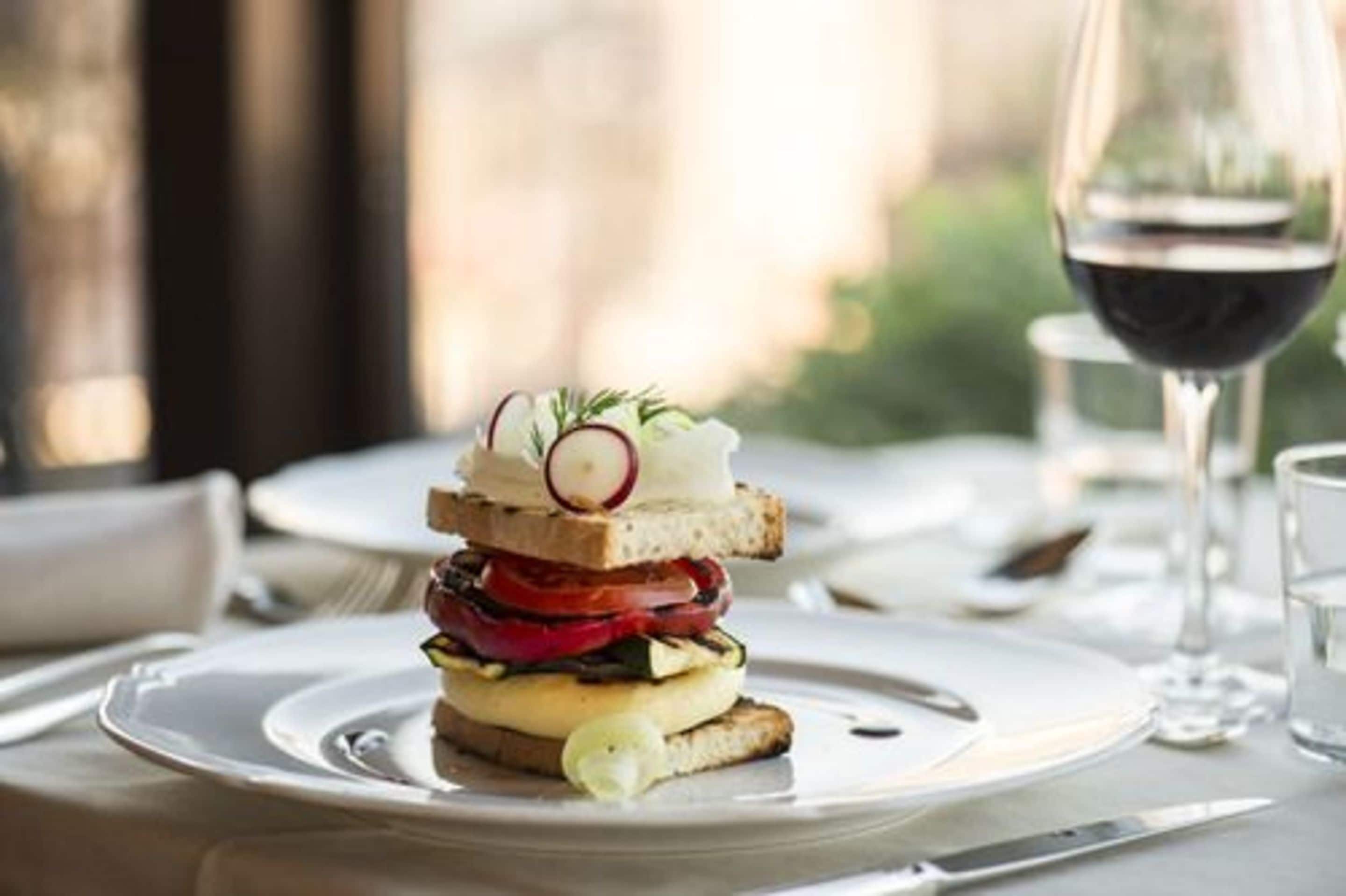 A neatly arranged dining table with plates, cutlery, and a glass of red wine.