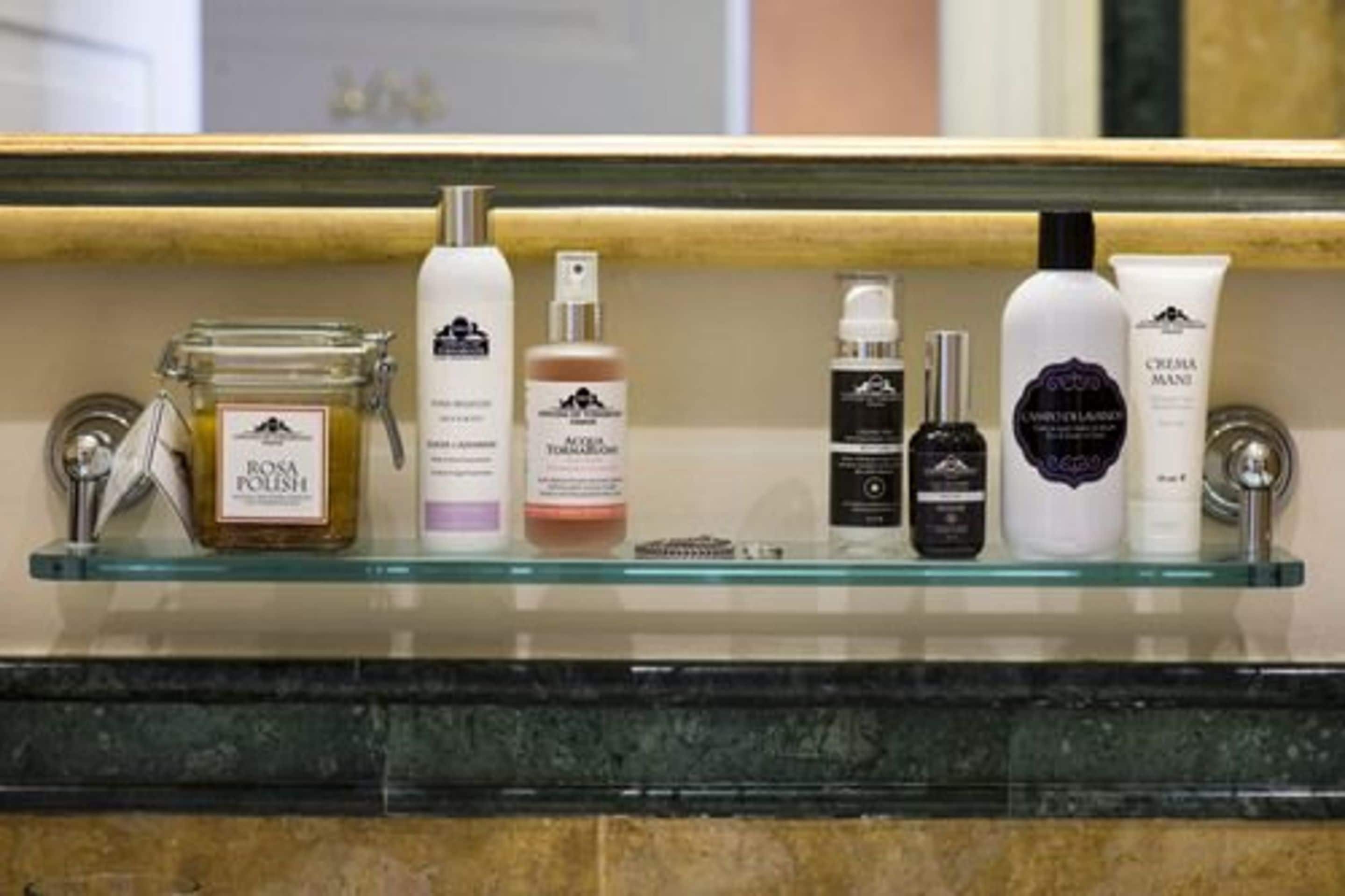 A bathroom shelf with various toiletries including a jar of Rosa Polish, a bottle of toner, and a tube of cream.