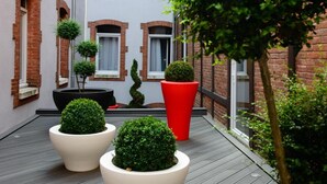 Un patio estrecho con plantas en macetas y una terraza de madera.