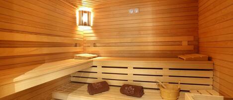 Un sauna en bois avec des bancs, un réchauffeur de banc et un seau.
