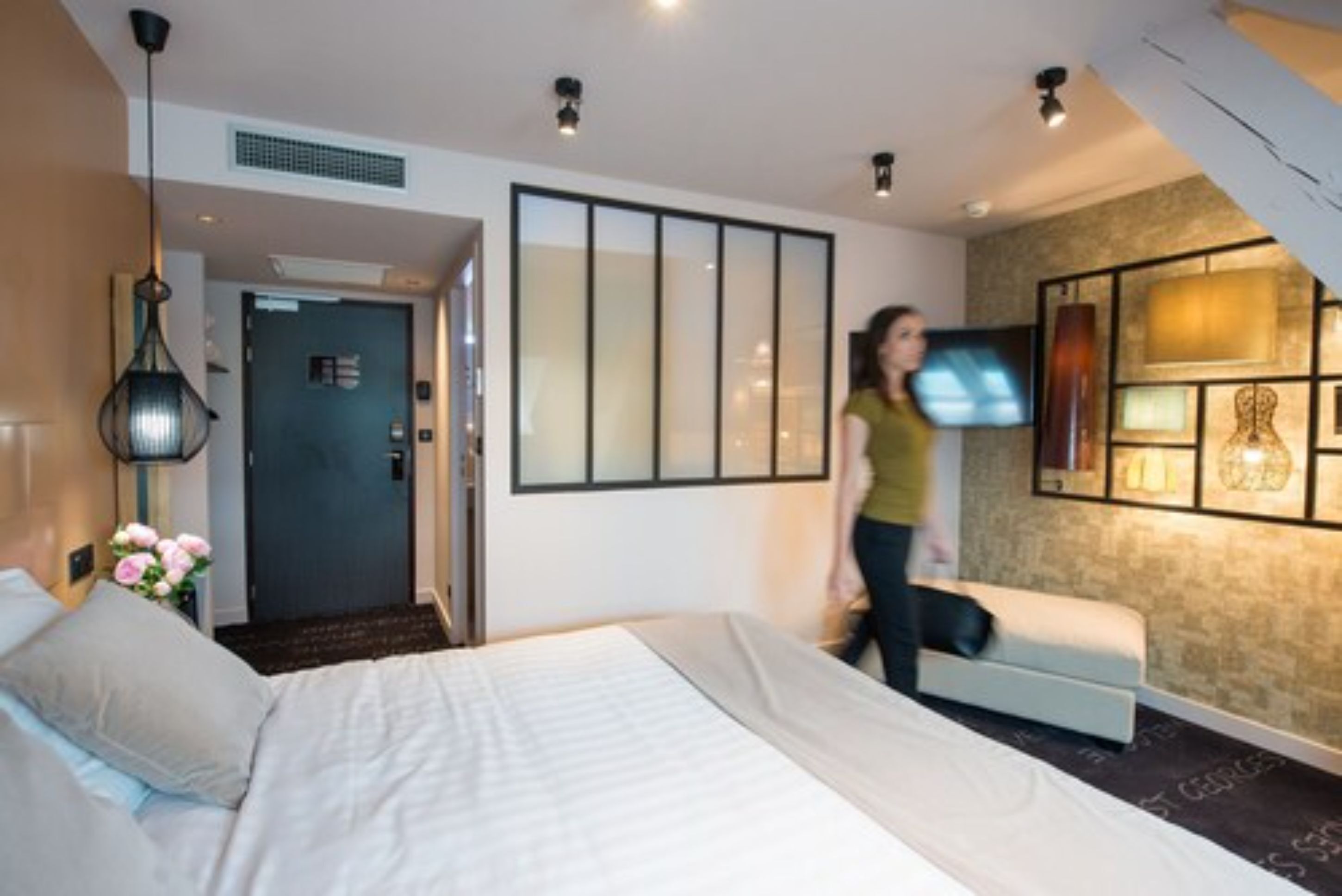 Une chambre d’hôtel moderne équipée d’un lit, d’un canapé, d’une télévision et d’un mur décoratif.