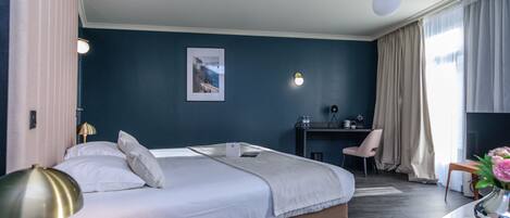 Habitación de hotel con una cama grande, un escritorio, una silla y una mesita con un jarrón de flores.