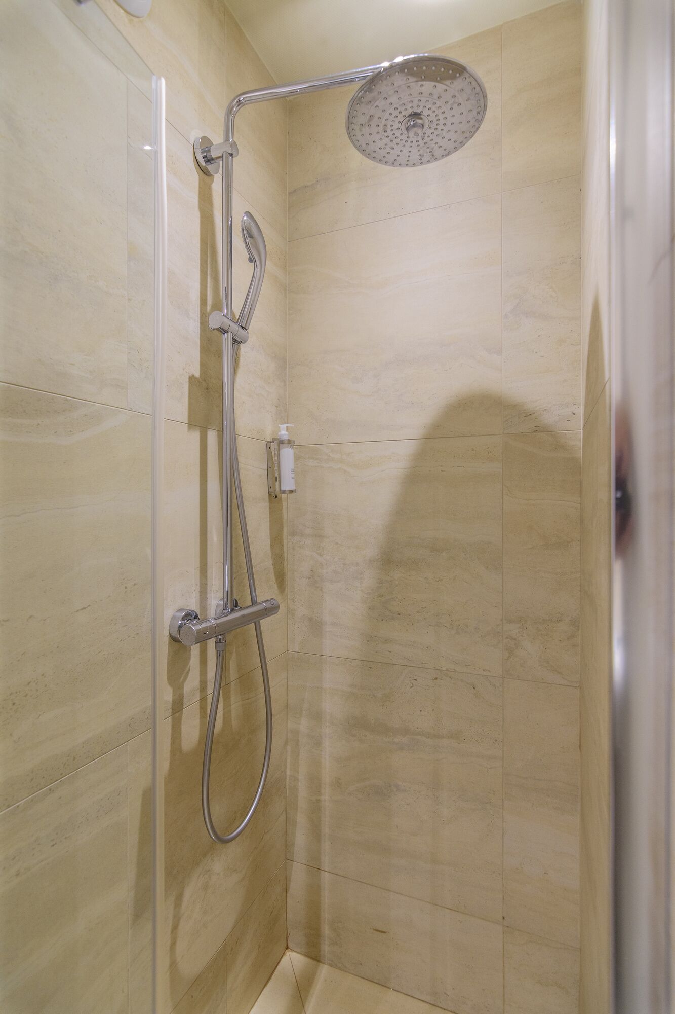 A shower with a handheld showerhead and a wall-mounted rain showerhead in a tiled room.
