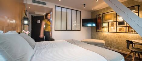 A modern hotel room with a large bed, a desk, and a TV mounted on the wall.