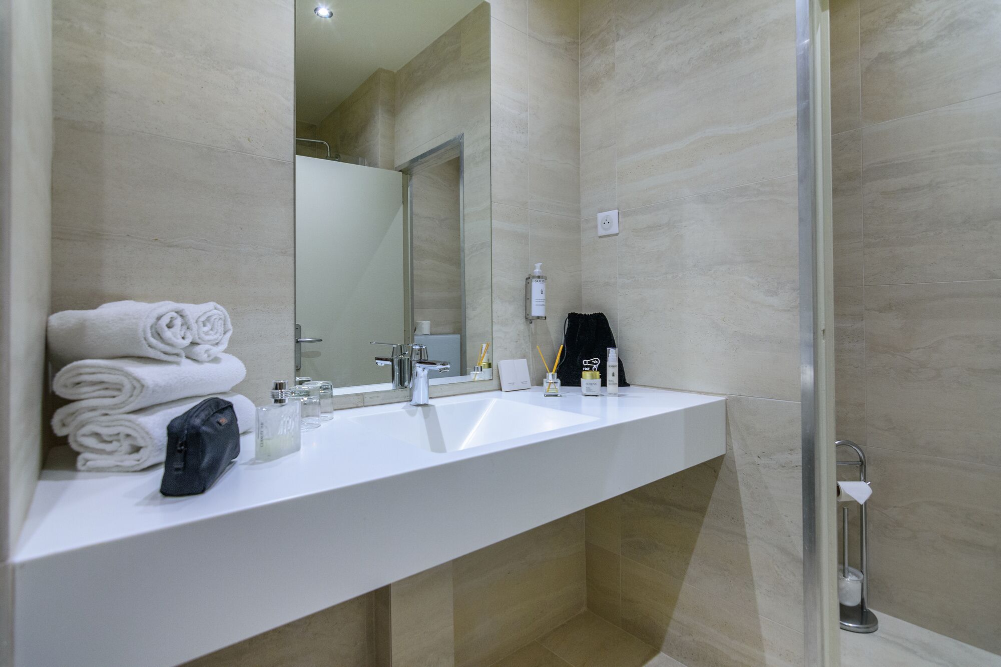 A modern bathroom with a white sink, two mirrors, and a glass shower enclosure.