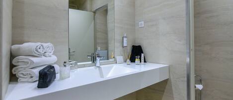 Un baño moderno con lavamanos blanco, dos espejos y cabina de ducha de vidrio.
