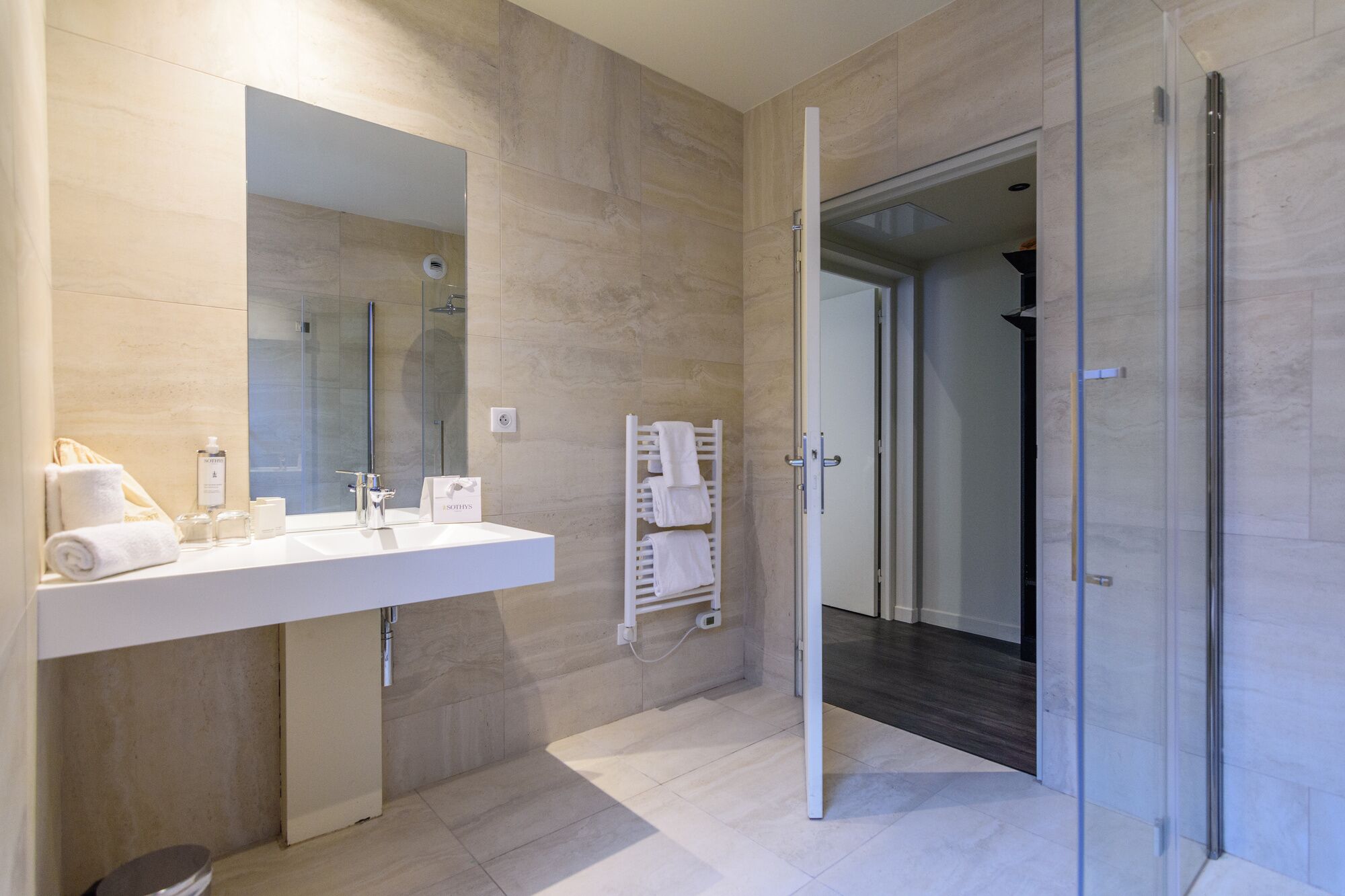 A modern bathroom with a white vanity, a glass shower enclosure, and a towel rack.