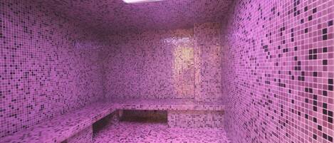 Una habitación con paredes y suelo de mosaico rosa, un banco y un tragaluz.