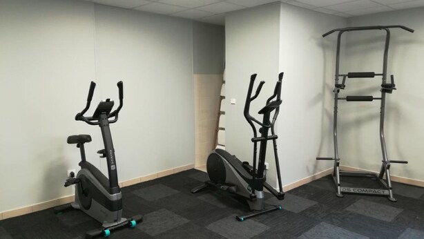 A fitness room with two stationary bikes and a compact weight machine.