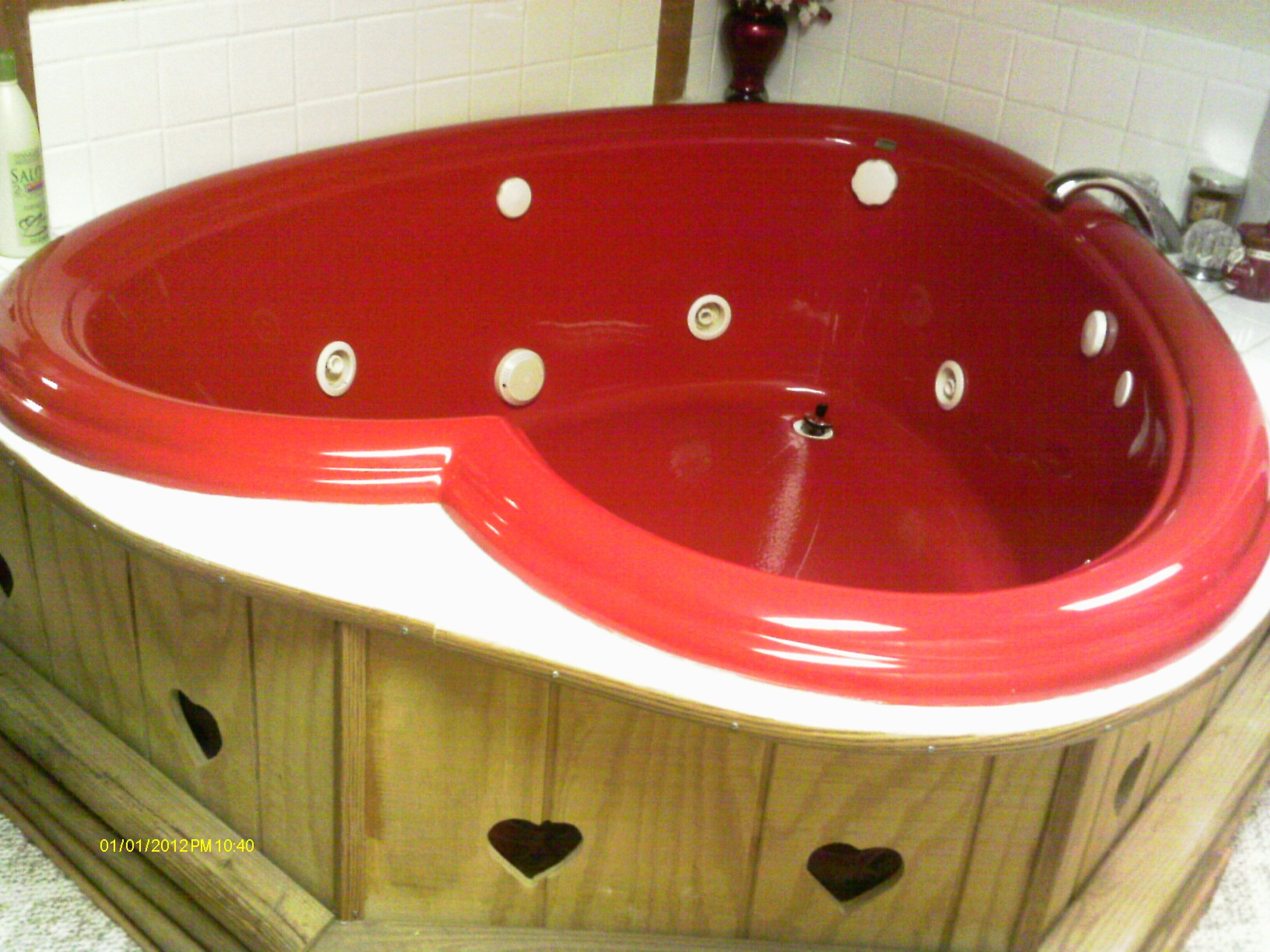 Un jacuzzi rouge avec des découpes en forme de cœur sur le meuble en bois.
