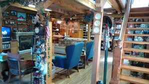 A cozy room with a fireplace, a sofa, and various decorative items including clocks and a sign that says "Plus". - Kennedys Red Barn Inn (Perry)
