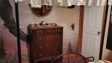 Une chambre à coucher avec un lit, une commode, un miroir et une porte.