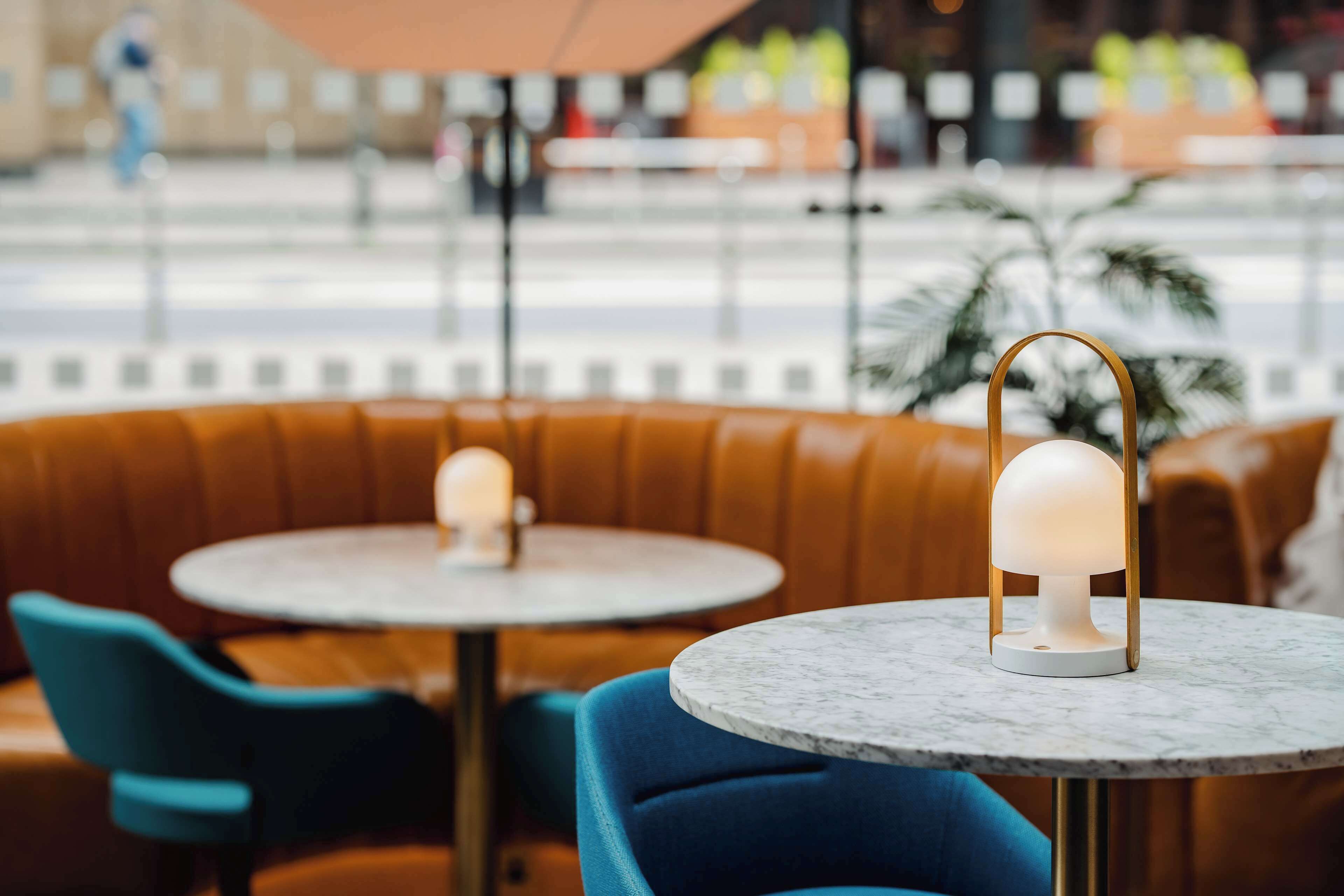 A seating area with a round table and a lamp, featuring a marble top and a blue chair.