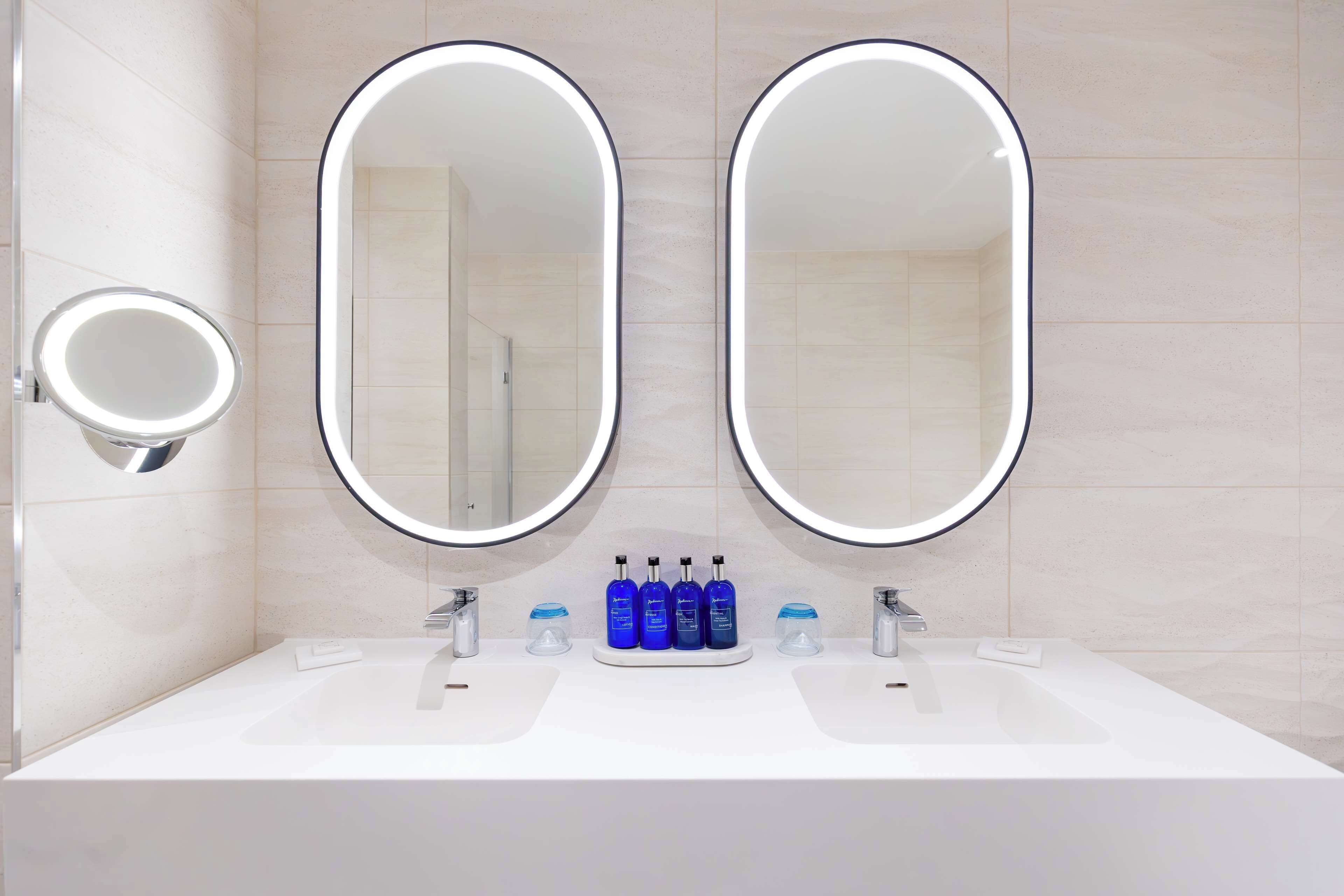 A bathroom with two large mirrors, a sink, and a vanity.