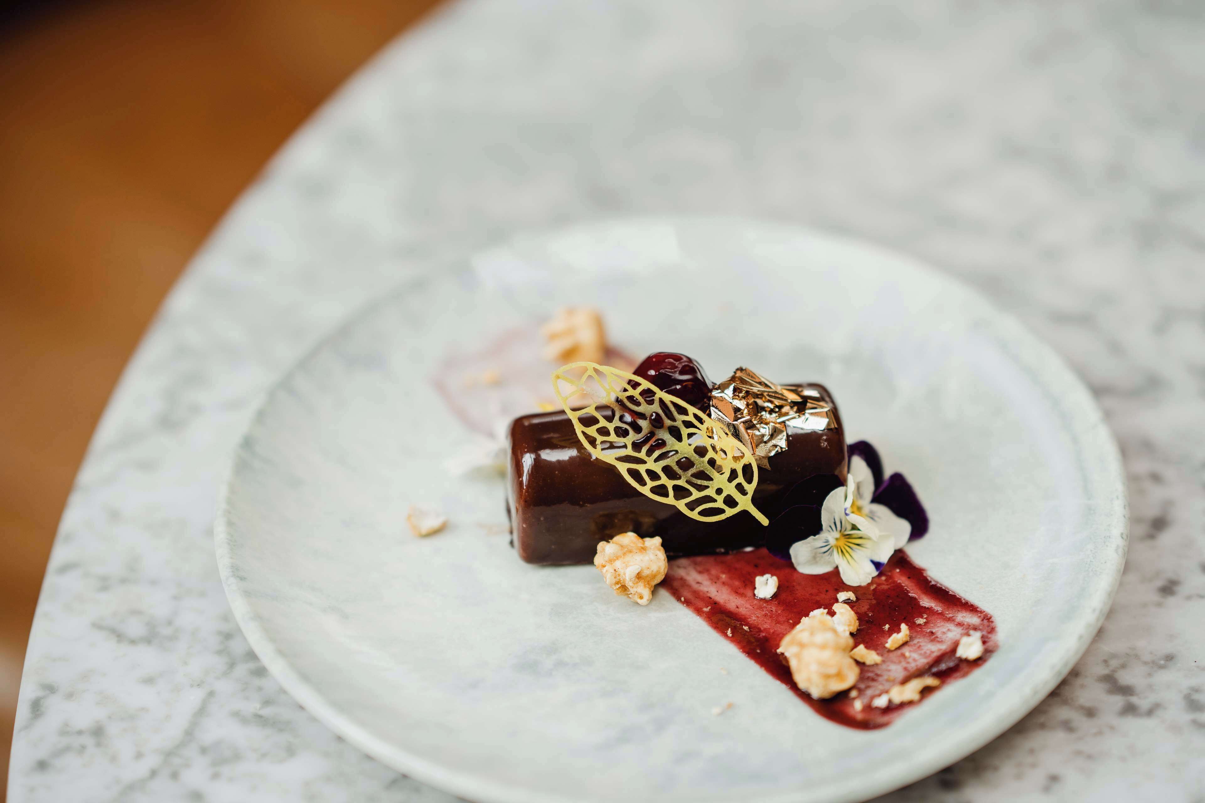 Un postre en un plato con decoración de hoja y una flor.