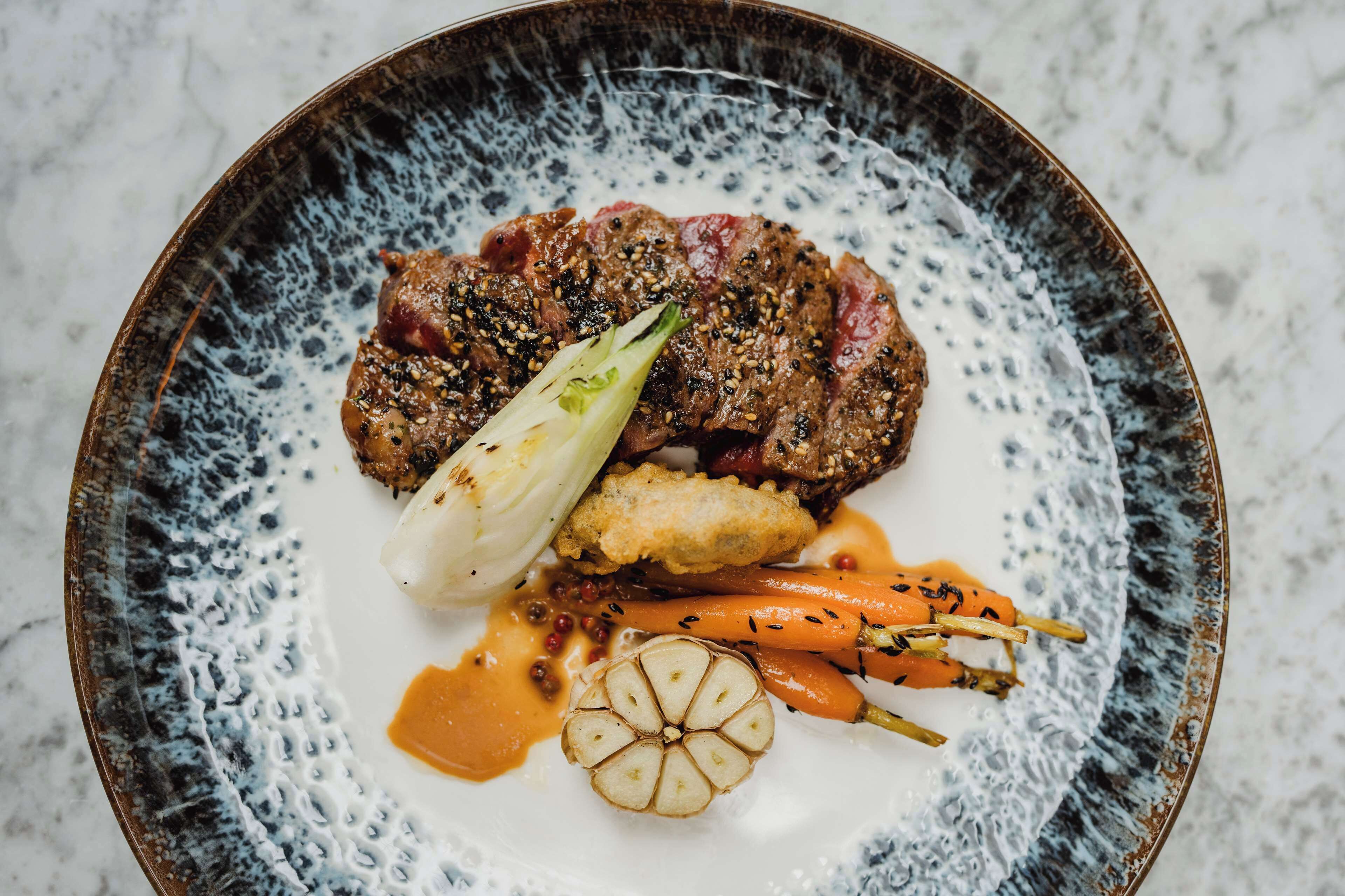 A plate of food with a piece of meat, vegetables, and a sauce.