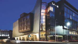 Un hôtel moderne au design original, caractérisé par des lignes angulaires, de grandes fenêtres et une enseigne bien visible portant le nom « Radisson ».