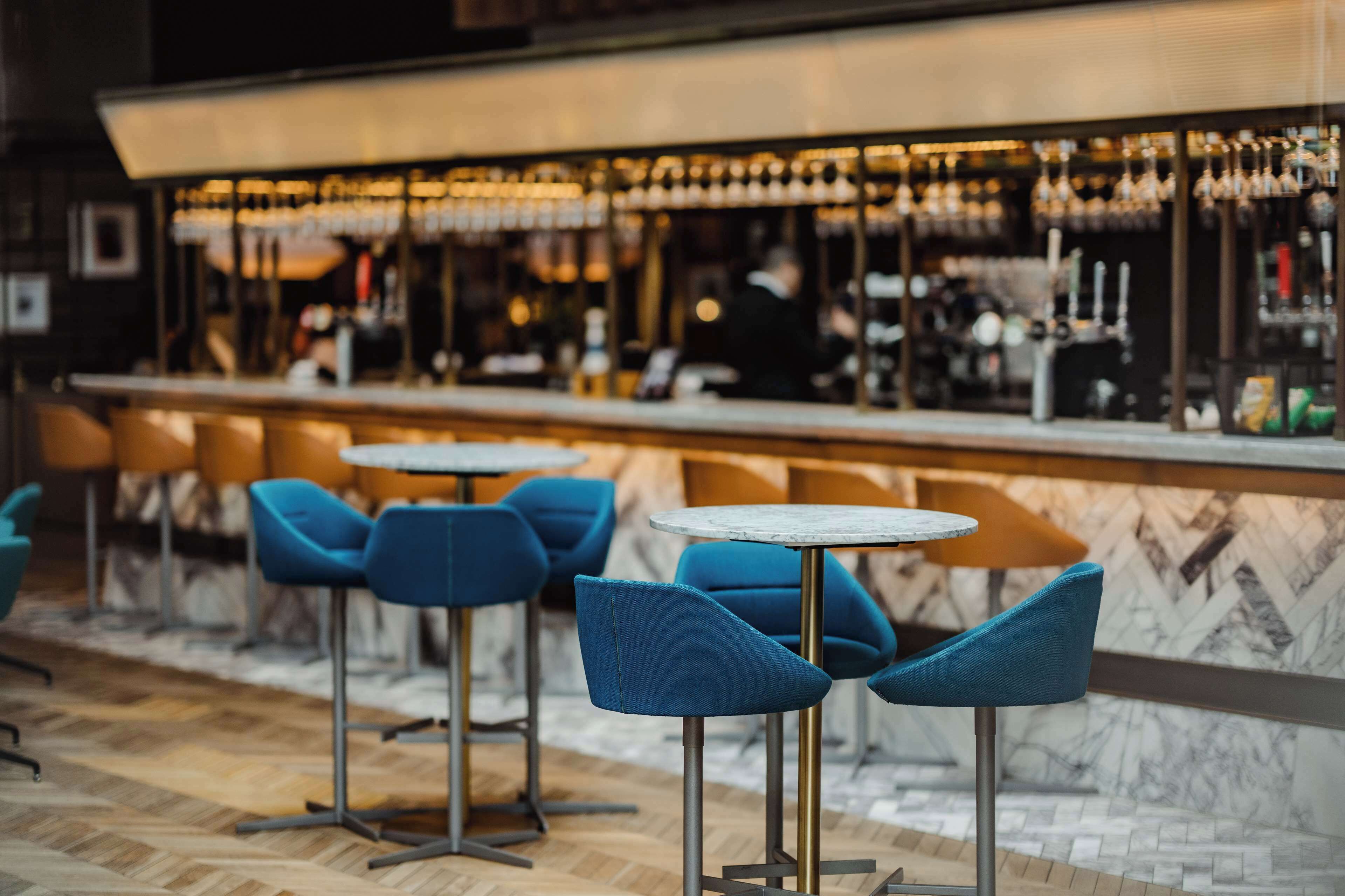 A bar area with blue chairs and a marble counter.
