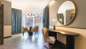 Une chambre d’hôtel dotée d’un coin repas, d’un grand miroir rond et offrant une vue sur le paysage urbain grâce à de larges fenêtres.