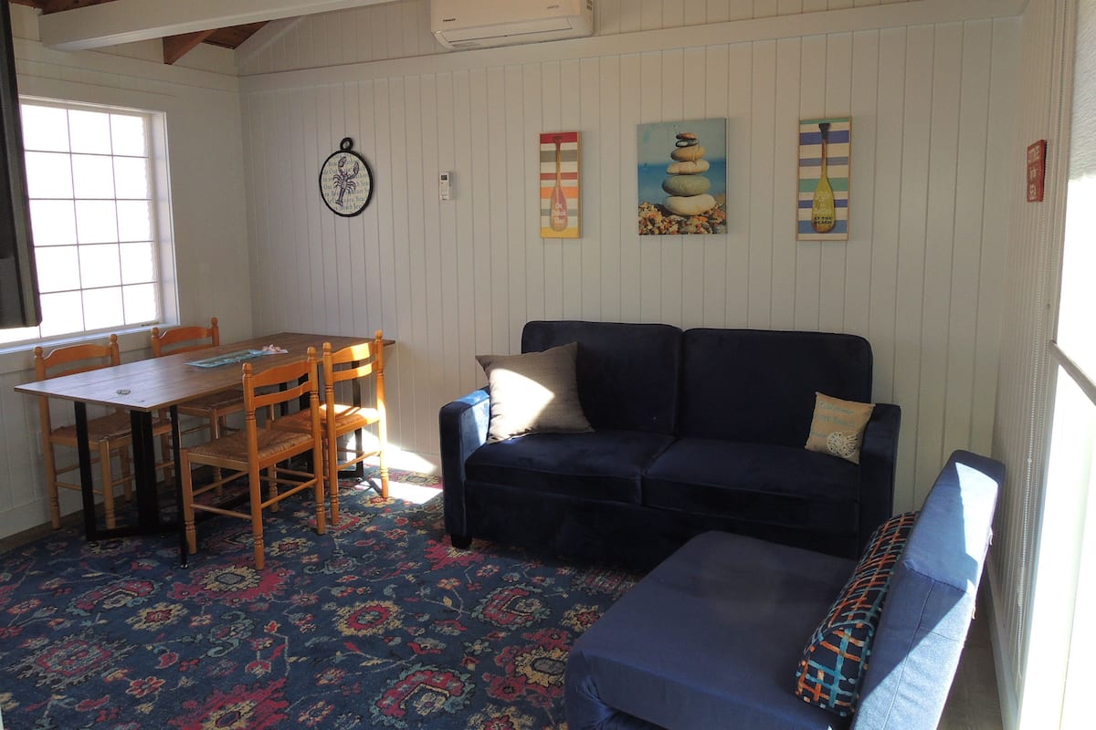 A cozy room with a wooden dining table, a blue sofa, and a patterned carpet.