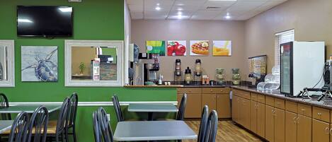 Interior de restaurante con paredes verdes, suelo de madera y mostrador con diversos alimentos y electrodomésticos.