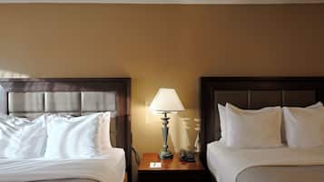 Una habitación de hotel con dos camas, una mesita de noche con lámpara y un teléfono.
